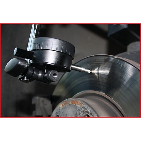 Nahaufnahme eines schwarzen Messgeräts, das die Bremsscheibe eines Autos inspiziert.